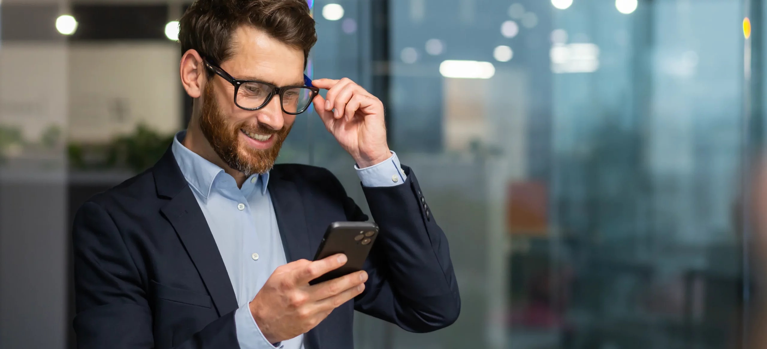 Homme en costume souriant qui consulte son smartphone